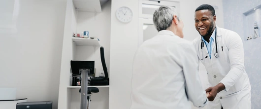 Medical professional and patient smiling and holding hands 