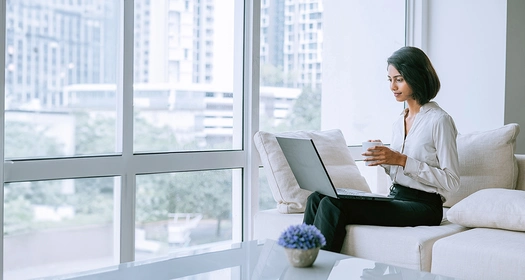 Eine Person mit einem Computer sitzt auf einem Sofa