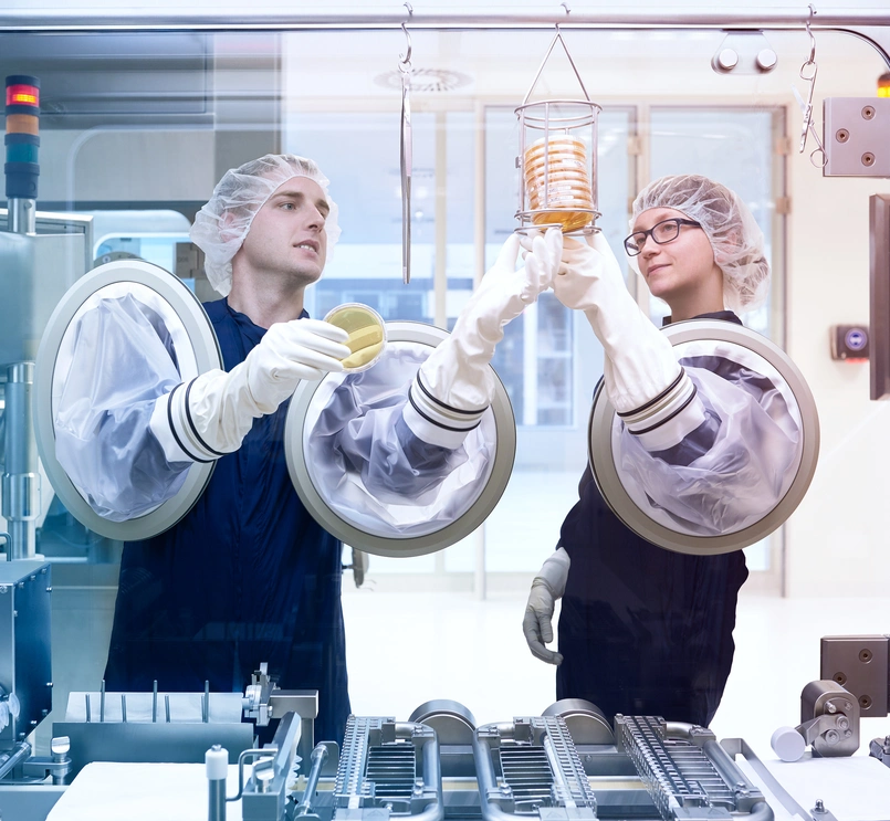 Two production specialists work on a machine