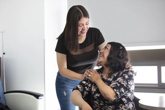 Paciente y cuidadora mirandose y abrazandose 